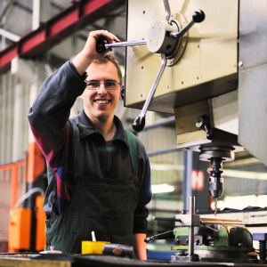Happy machinist using machine in manufacturing plant