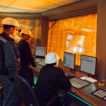Three men in hard hats looking at a computer