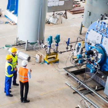 Men in hardhats looking at large machine