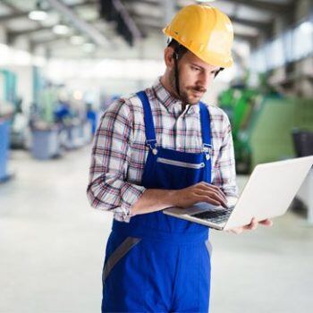 Man on shop floor holding laptop