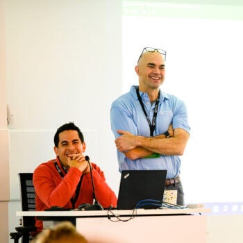 Two men smiling with one sitting and one standing