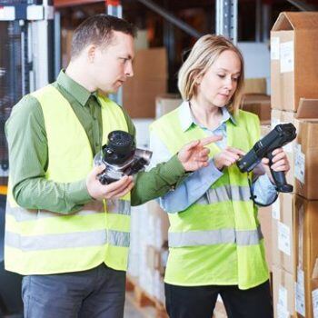 Two people working on handheld devices in a warehouse