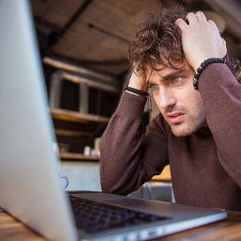 man looking at laptop and grabbing his hair