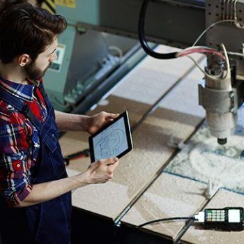 Man looking at iPad with machine working