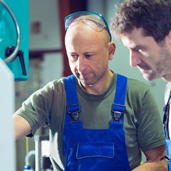 Man in overalls looking at machine