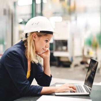 Woman in hard hat looking at laptop