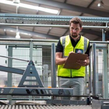 Man with clipboard looking at manufacturing line