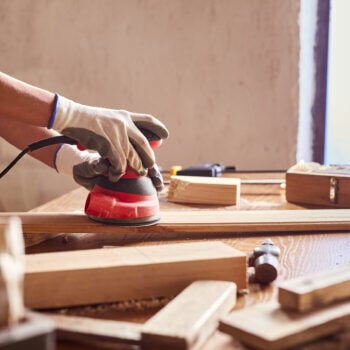 man's hand sanding wood