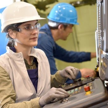 Woman in hardhat looking at machine