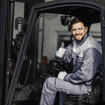 Man on forklift looking at the camera and giving a thumbs up