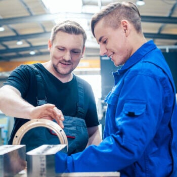 Two manufacturing men working on a machine