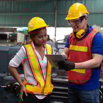 Two people in hard hats looking at iPad