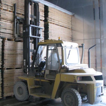 Forklift in front of stacks of wood