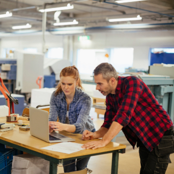 man and woman looking at a laptop while in a manufacturing shop