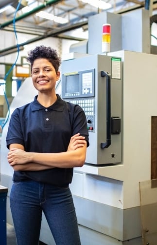 Smiling female manufacturer in front of machine on shop floor