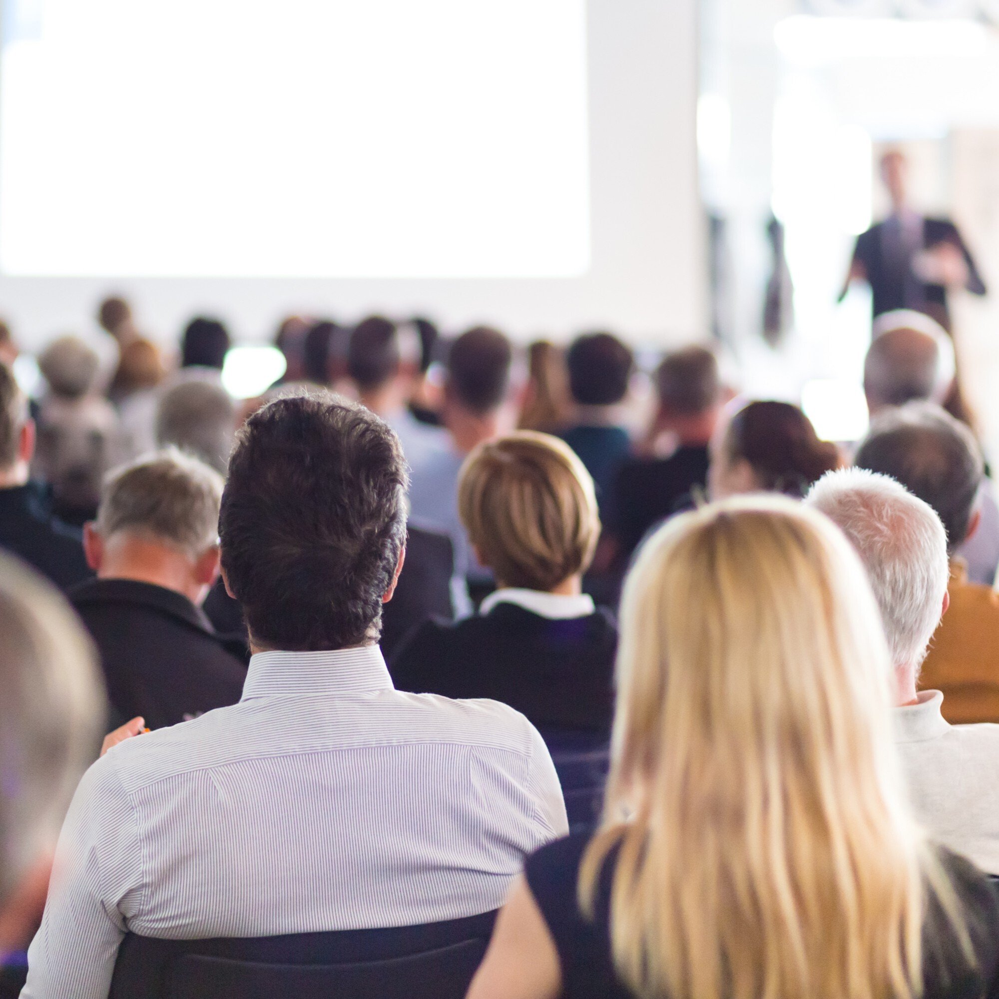 People in business attire attending a manufacturing conference session